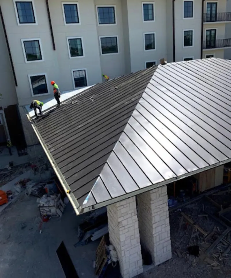 Crew installing standing seam metal roof panels on a commercial project in Rockford